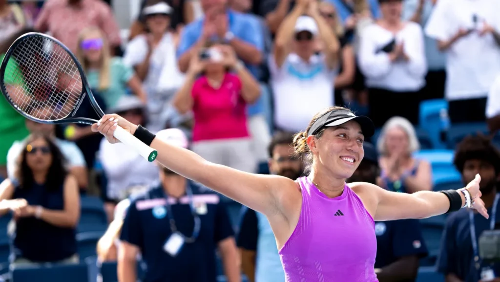 tennis player smiles and holds up her raqcuet