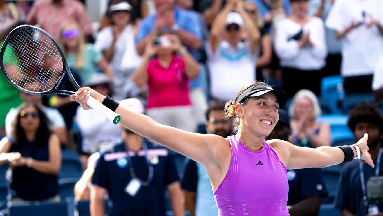 tennis player smiles and holds up her raqcuet