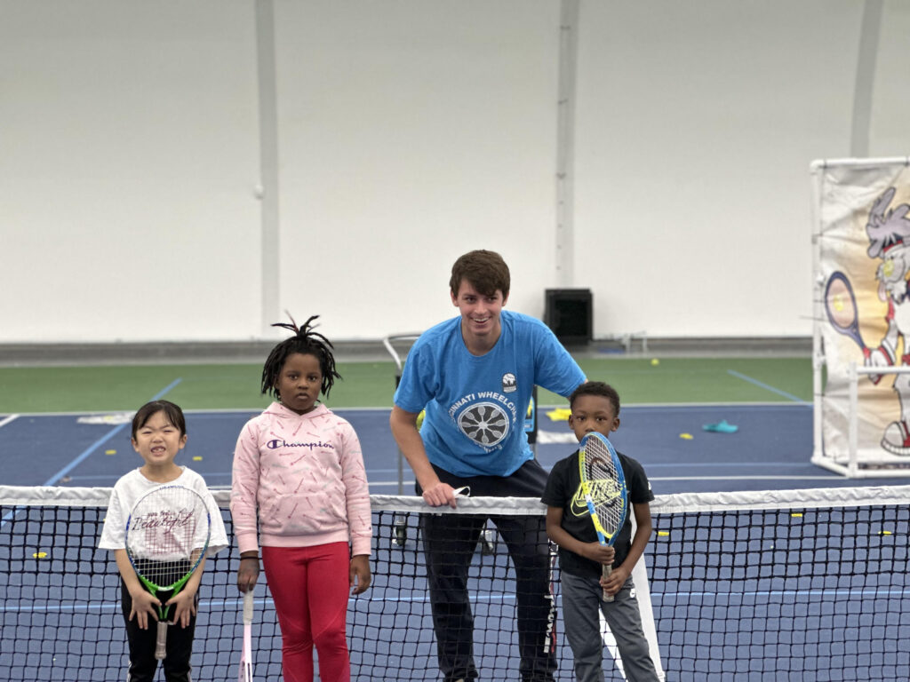 coach posing with young tennis students