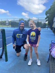 coach posing with young tennis student