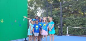 coach posing with young tennis students