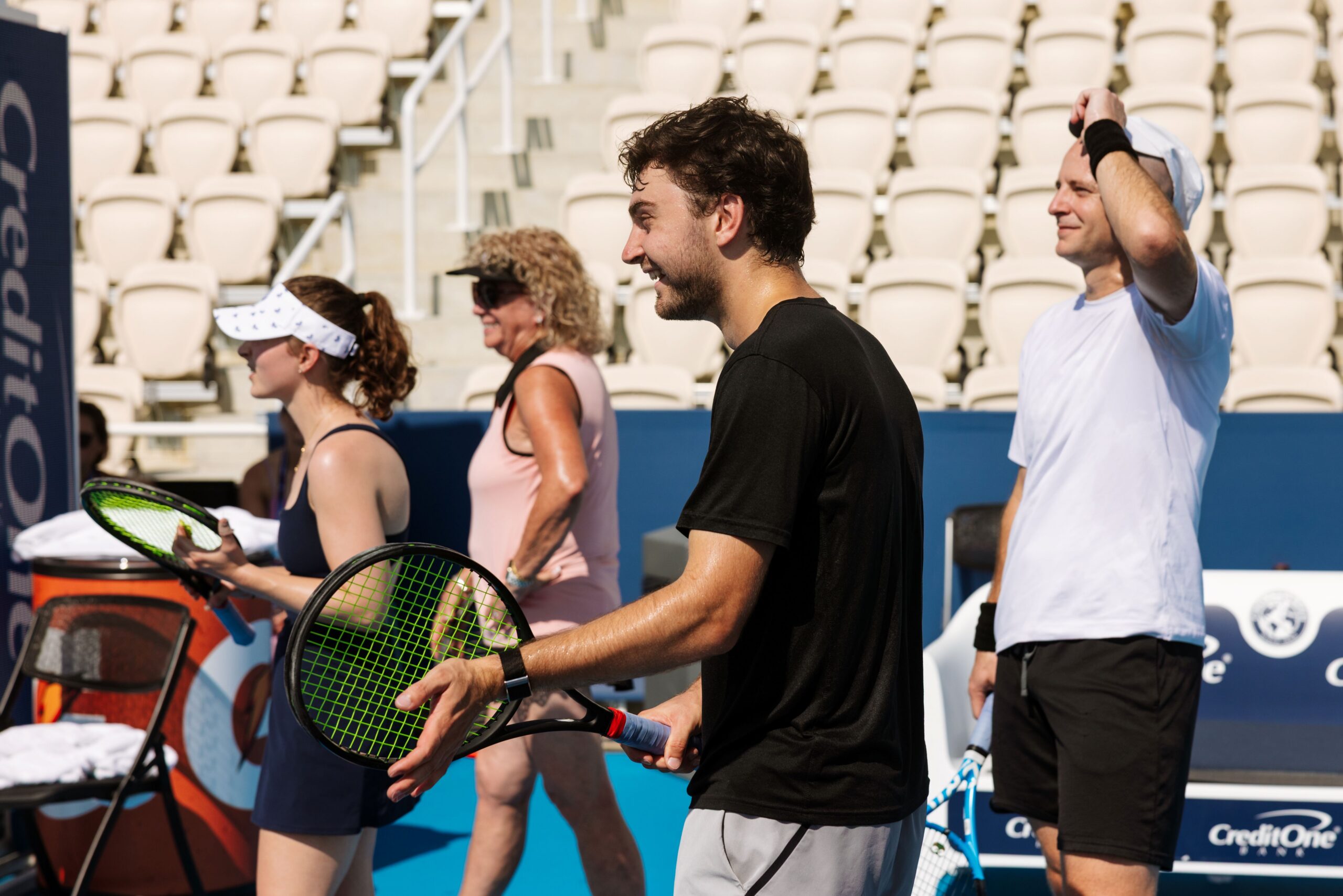 adults smiling participating in a tennis clinic
