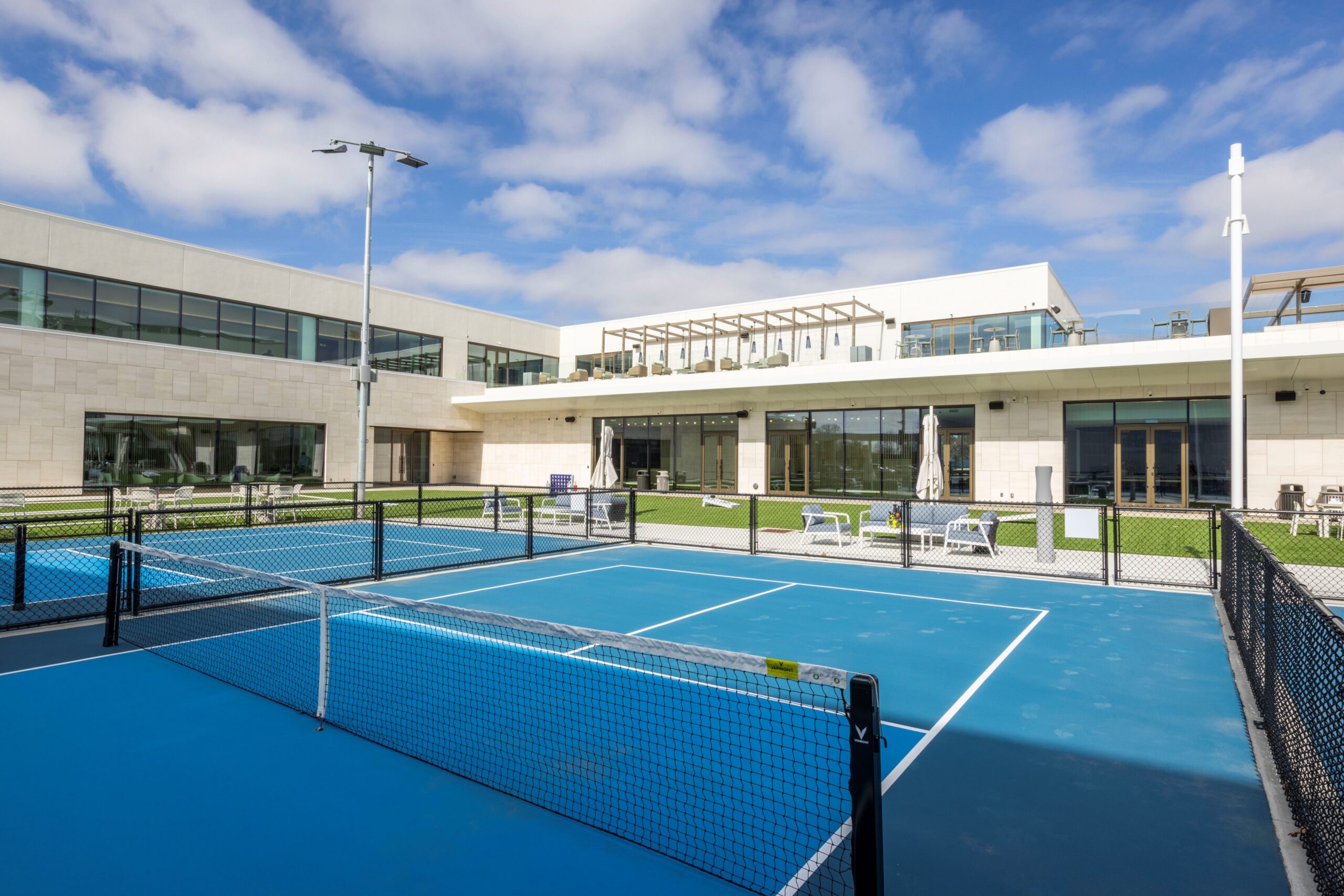 Outdoor tennis court with turf and Cincinnati Open Sporting Club behind it