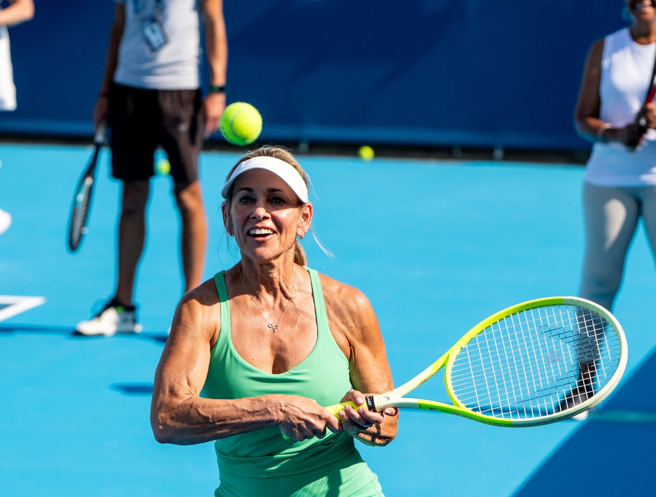 Woman in green dress prepares to hit a tennis ball with a racquet