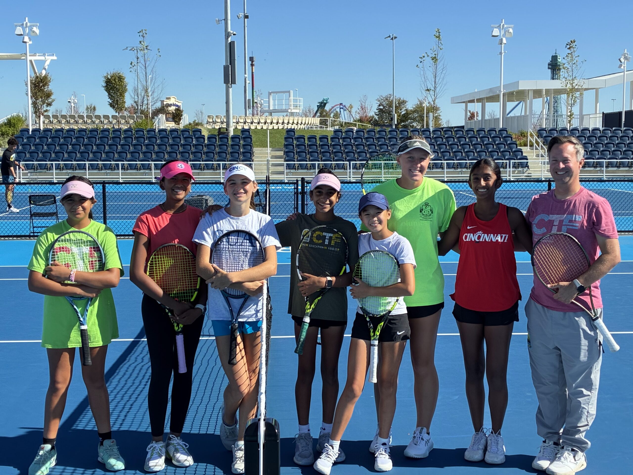 Group of people smiling at the camera holding tennis racquets at the Cincinnati Open Sporting Club