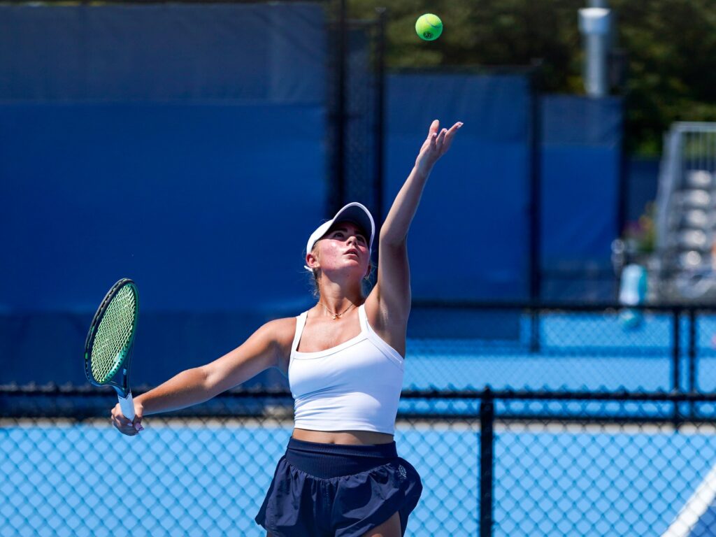 Girl serving tennis ball at tennis clinic