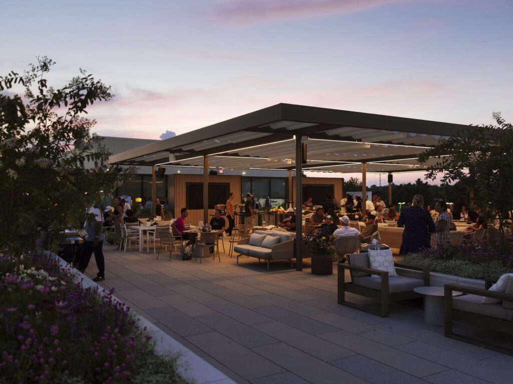 Rooftop outdoor lounge at dusk with people seated.