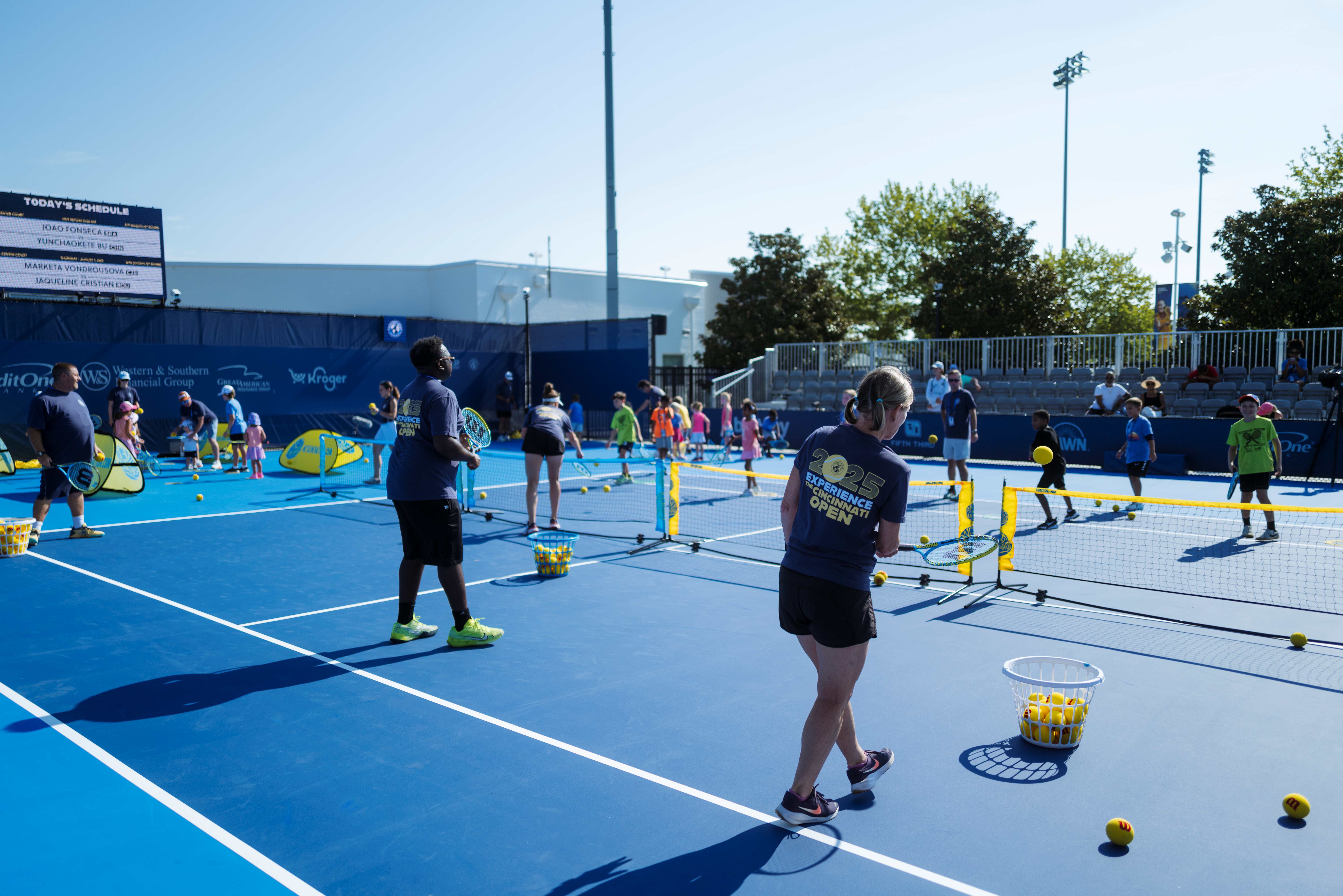 Volunteers playing tennis with kids on a mini court
