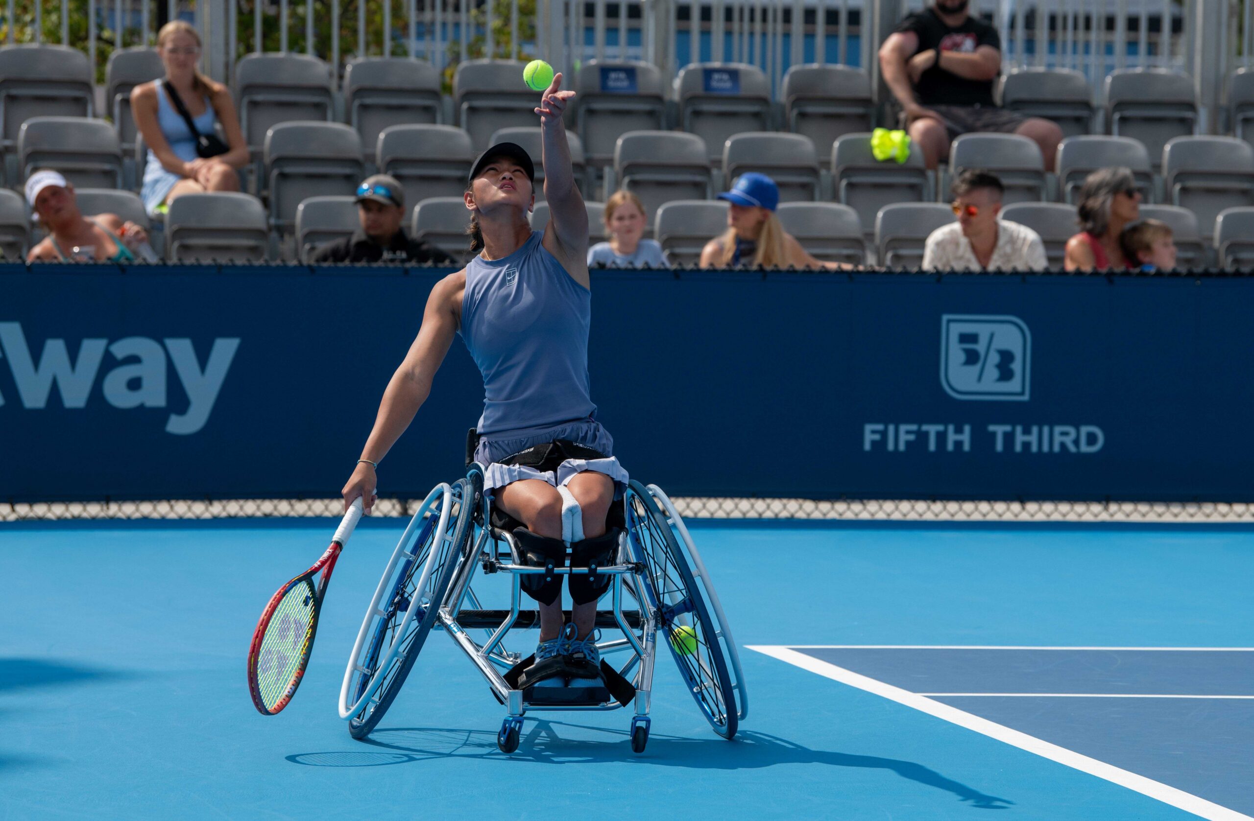 Wheelchair tennis player tossing ball in the air ready to serve