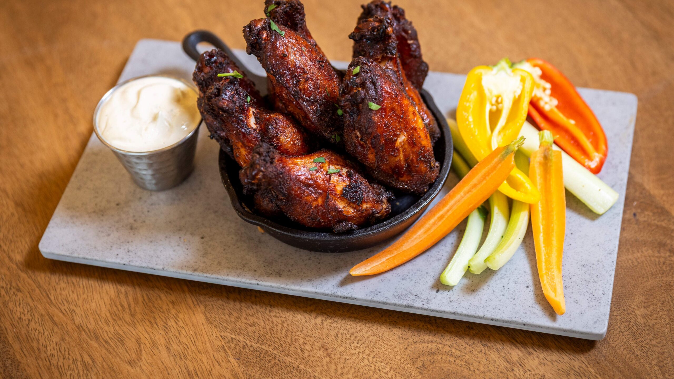 Crispy wings in a bowl with a side of ranch and celery and peppers